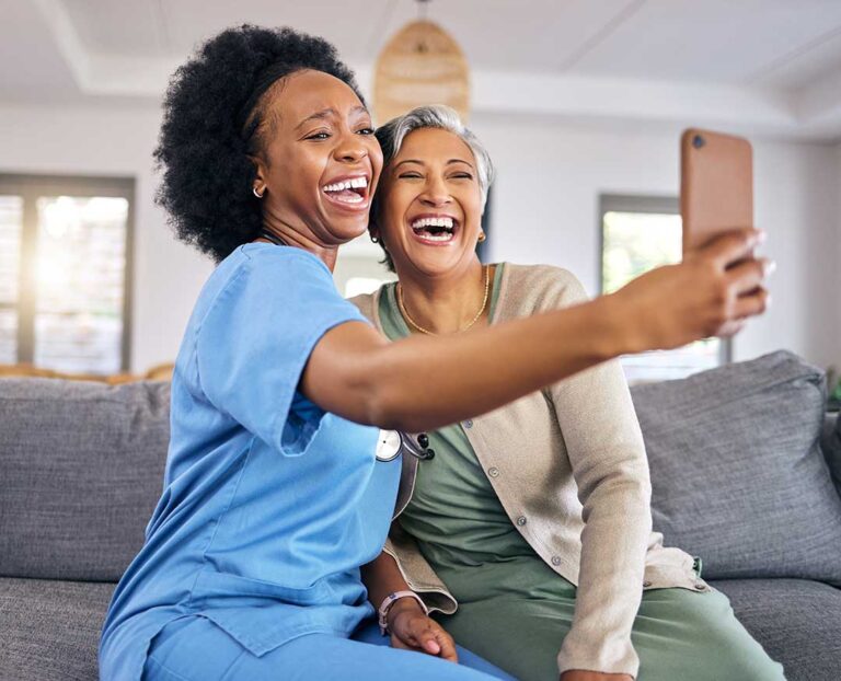 Older adult reviews a care tablet with a caregiver in a bright assisted living apartment.